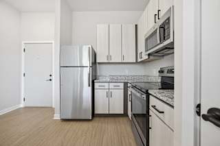 A kitchen with a refrigerator, microwave, oven, and cabinets.
