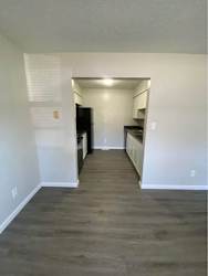 a renovated living room and kitchen with white walls and wood floors
