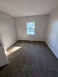 an empty room with a window and a carpet