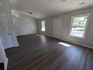 an empty living room with wooden floors and a window