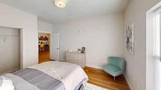 A bedroom with a bed, dresser, and chair.