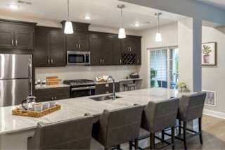 A kitchen with a large island and grey chairs.