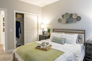 A bedroom with a bed, nightstand, and a wall decoration.