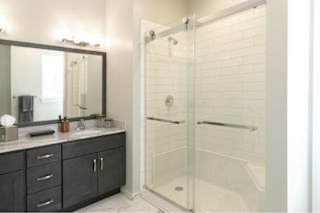 A bathroom with a walk-in shower and a vanity with a mirror.