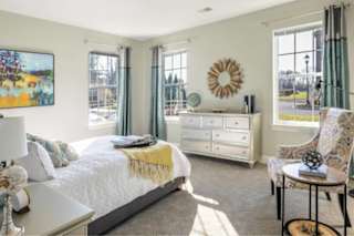 A bedroom with a bed, a chair, and a dresser.