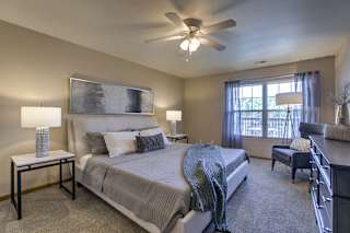 A bedroom with a large bed and a ceiling fan. at Tranquility Pointe, Omaha