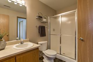 A bathroom with a toilet, sink, and mirror. at Tranquility Pointe, Omaha