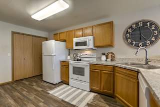A kitchen with a white refrigerator, wooden cabinets at Tranquility Pointe, Omaha