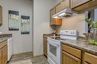 A kitchen with a white stove top oven and wooden cabinets. at The Pointe, LaVista, NE