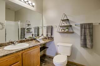 A bathroom with a toilet, sink, and shelves. at The Pointe, LaVista, NE, 68128