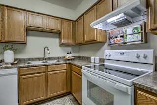 A kitchen with a white oven and wooden cabinets. at The Pointe, Nebraska, 68128