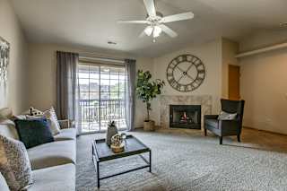 A living room with a fireplace, a couch, a chair, a coffee table, and a ceiling fan. at The Pointe, Nebraska