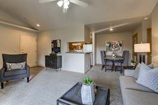 A living room with a grey couch, a black chair, and a coffee table. at The Pointe, LaVista, NE