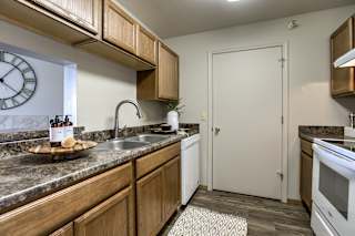 A kitchen with wooden cabinets and a white door. at The Pointe, LaVista, Nebraska