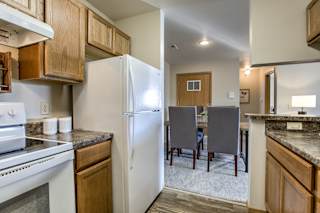 A kitchen with a white refrigerator and wooden cabinets. at The Pointe, LaVista, Nebraska