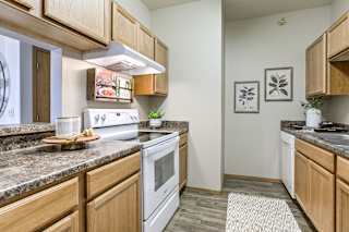 A kitchen with wooden cabinets and a granite countertop. at The Pointe, LaVista, Nebraska