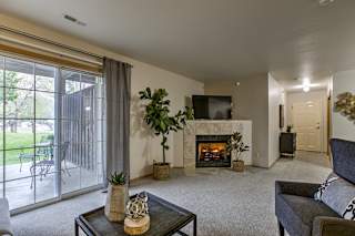 A living room with a fireplace and sliding glass doors. at The Pointe, LaVista, Nebraska