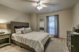 A bedroom with a large bed and a ceiling fan. at The Pointe, Nebraska