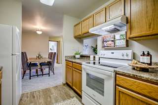 A kitchen with a white stove and wooden cabinets. at The Pointe, LaVista, NE, 68128