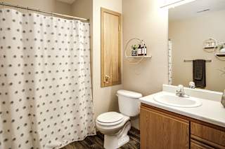 A white toilet sits next to a sink in a bathroom. at Tranquility Pointe, Omaha, 68164
