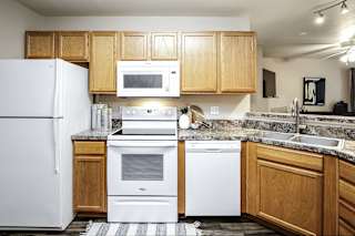 A kitchen with white appliances and wooden cabinets. at Tranquility Pointe, Nebraska