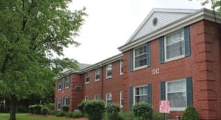 A red brick building with green shutters and a white sign on the front at Michigan Street Apartment Homes, Grand Rapids  , MI, 49503