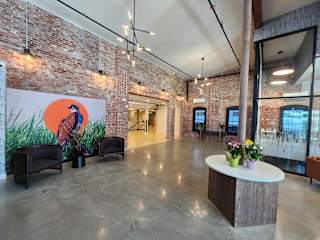 A room with a large mural of a bird on a wall and a round table with flowers on it.