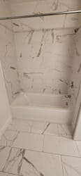 A white marble tiled shower with a white tub.