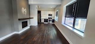 A long hallway with wood floors and a fireplace.
