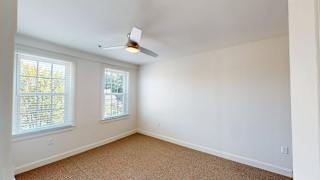Spacious bedroom with beige carpet and ceiling fan at Bostonian Shoe Lofts Apartments, Whitman, Massachusetts