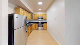 Compact kitchen with stainless appliances and wood cabinets at Bostonian Shoe Lofts Apartments, Massachusetts