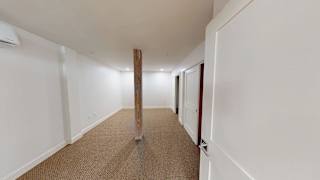 A long hallway with a carpeted floor and white walls.