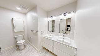 A white bathroom with a toilet, sink, and mirror.