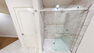 A bathroom with a walk-in shower and a white door.