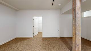 A room with a carpeted floor and a wooden pillar.