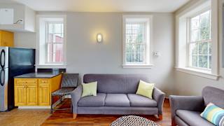 A grey couch with yellow pillows sits in a living room.