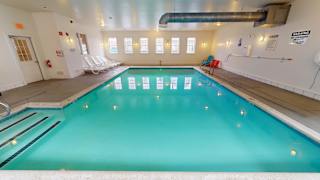 Indoor swimming pool with lounge chairs and windows at Bostonian Shoe Lofts Apartments, Whitman, MA 02382