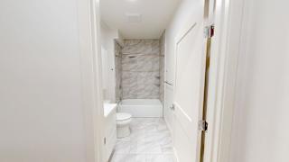 A white bathroom with a marble tiled shower.