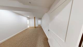 A long hallway with white walls and carpeted floor.