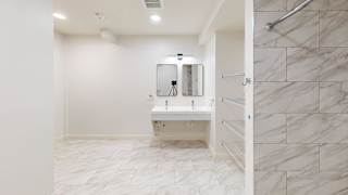 A bathroom with a white sink and marble tiles.
