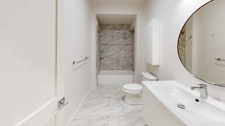 A white bathroom with a marble tile shower.