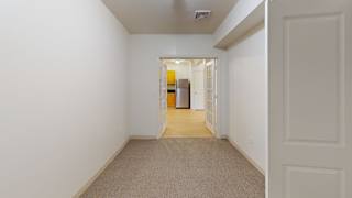 Empty carpeted room with hallway view to kitchen at Bostonian Shoe Lofts Apartments, Whitman, MA
