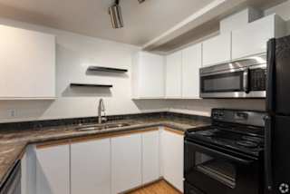 A modern kitchen with black appliances and white cabinets.