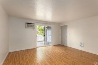 A room with wooden floors and white walls, featuring a sliding glass door.