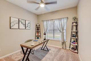 an office with a large window and a desk with a ceiling fan at Artisan Apartments & Shops, Austin