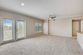 an empty living room with doors and a ceiling fan at Artisan Apartments & Shops, Texas, 78729