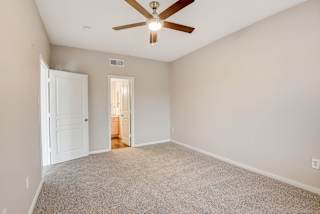 an empty living room with a ceiling fan and a door to a bathroom at Artisan Apartments & Shops, Austin, Texas, 78729