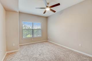 an empty living room with a ceiling fan and a window at Artisan Apartments & Shops, TX
