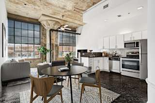 Adam Hats Lofts virtually staged kitchen and living area with stainless steel appliances, beautiful pillar and large windows | Deep Ellum Lofts in Dallas, TX