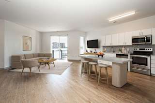 a living room with a kitchen and an island with chairs and a table at The Waterford At Rocketts Landing Apartments, PRG Real Estate, Richmond, Virginia